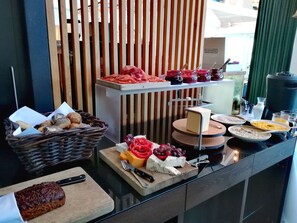 Montaje de bufé con diversos alimentos, incluyendo pan, queso y frutas.