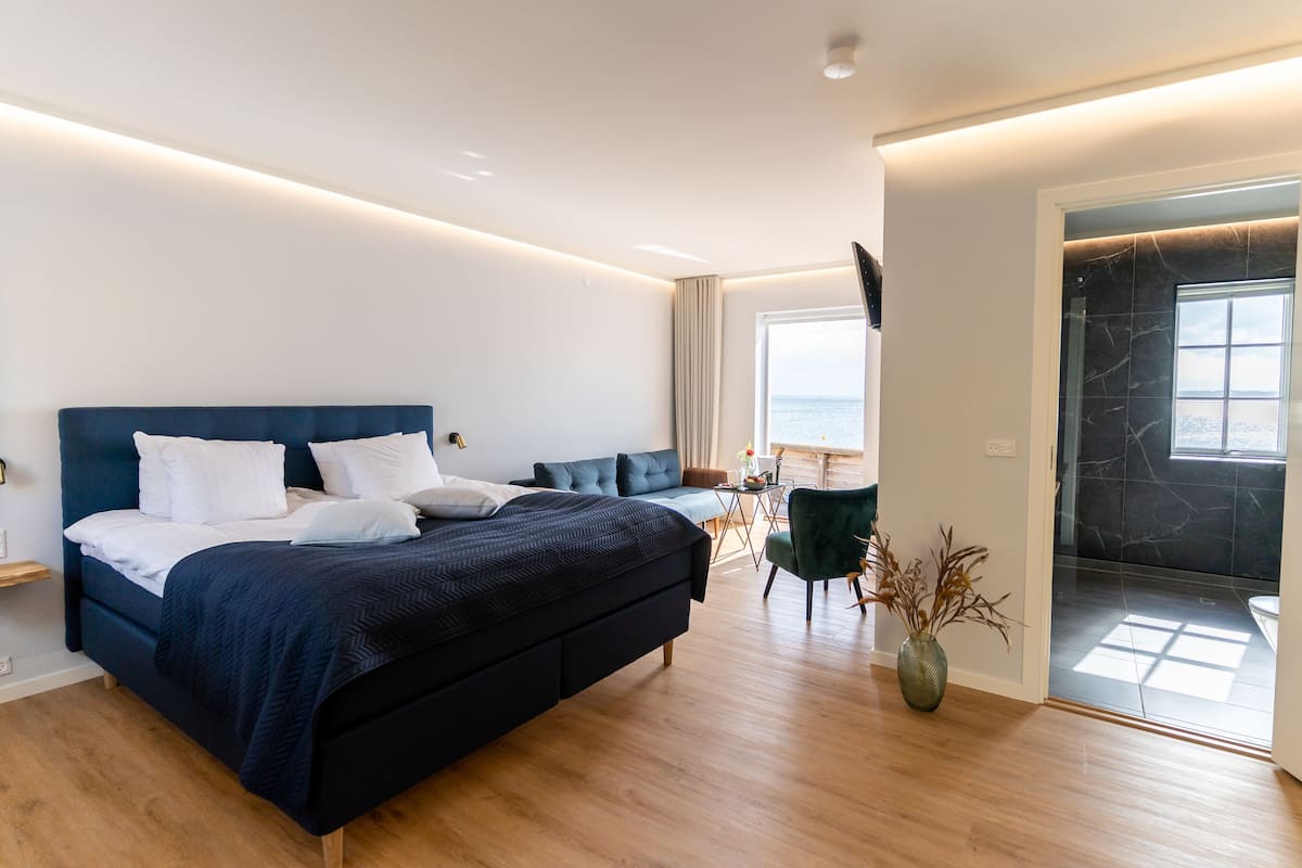 Un dormitorio moderno con una cama grande, un escritorio y vista al mar.