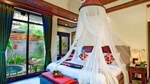 A bedroom with a canopy bed, a bedside table, a nightstand, and a view of the garden through a large window. - Intan Legian Seminyak Villa (Denpasar)