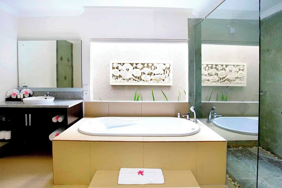 Un baño moderno con una bañera grande, un lavamanos independiente y una ducha con mampara de vidrio.