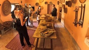 Un interior rústico con vigas de madera, una larga mesa con utensilios de cocina y diversos objetos de madera en las paredes.