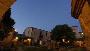 Un edificio histórico con un arco de piedra, un patio interior y un camino que lleva a la entrada.