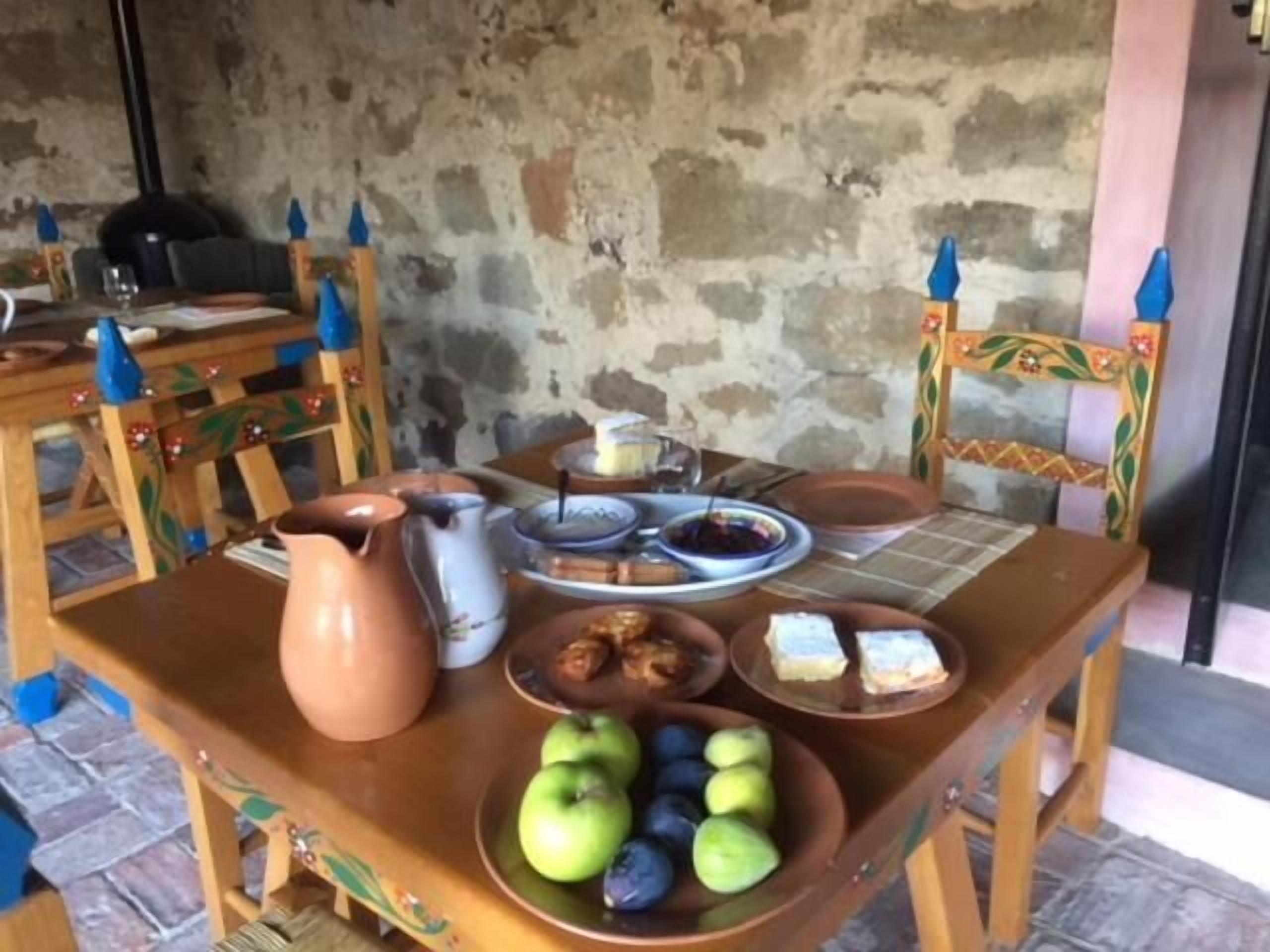 A table set with a pitcher, plates, bowls, and a bowl of fruit.
