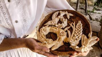 A person holding a basket with intricately carved white objects.