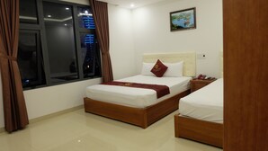 A hotel room with a bed, bedside table, and a window with curtains. - Seaside Hotel (Da Nang)