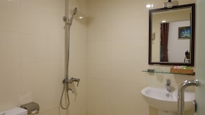 A bathroom with a shower, sink, and mirror. - Seaside Hotel (Da Nang)