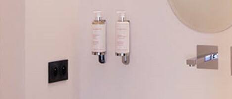 Un baño con un lavabo blanco, dos frascos de medicamentos, un espejo y un interruptor de luz.