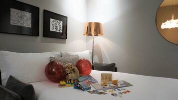 A neatly arranged hotel room with a bed, pillows, a lamp, and various items on the nightstand.
