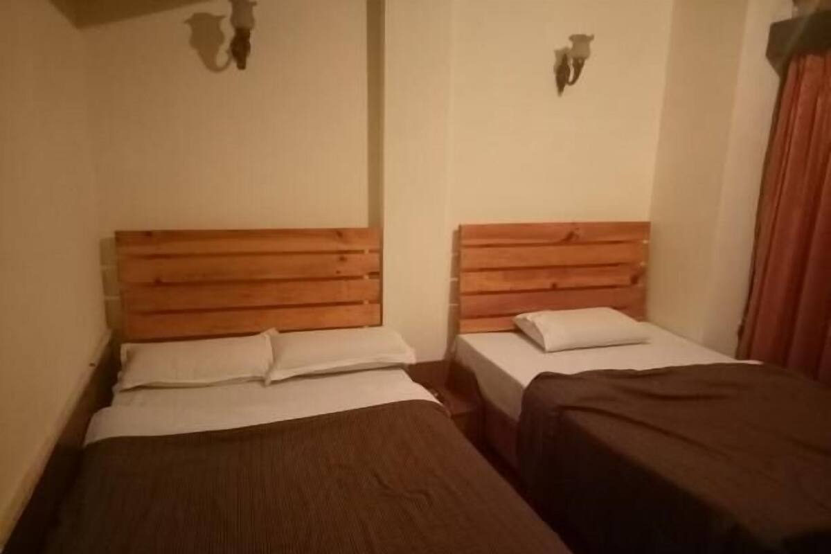 A room with two beds, each with wooden headboards and white bedding.