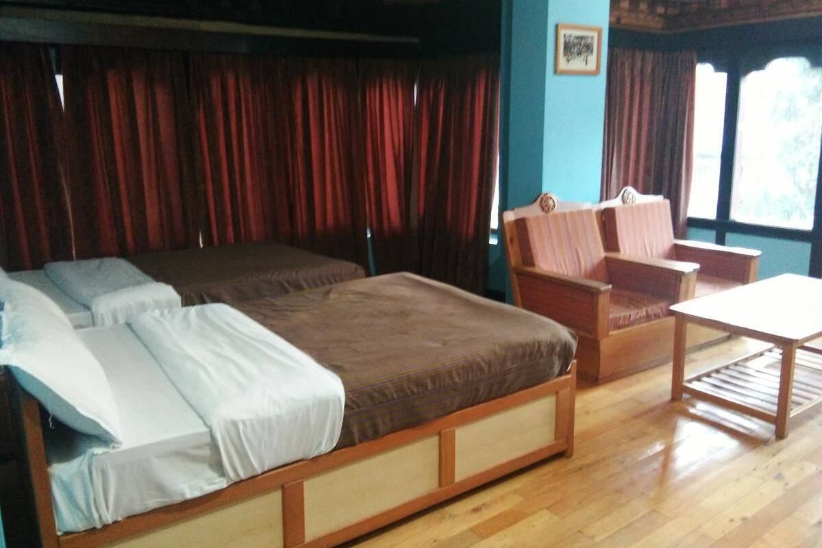 A room with a large bed, two chairs, and a small table.