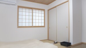 A bedroom with a bed, a window, a wardrobe, and a small black storage box. - Guest House Aoi Nakamoto (Kyoto)
