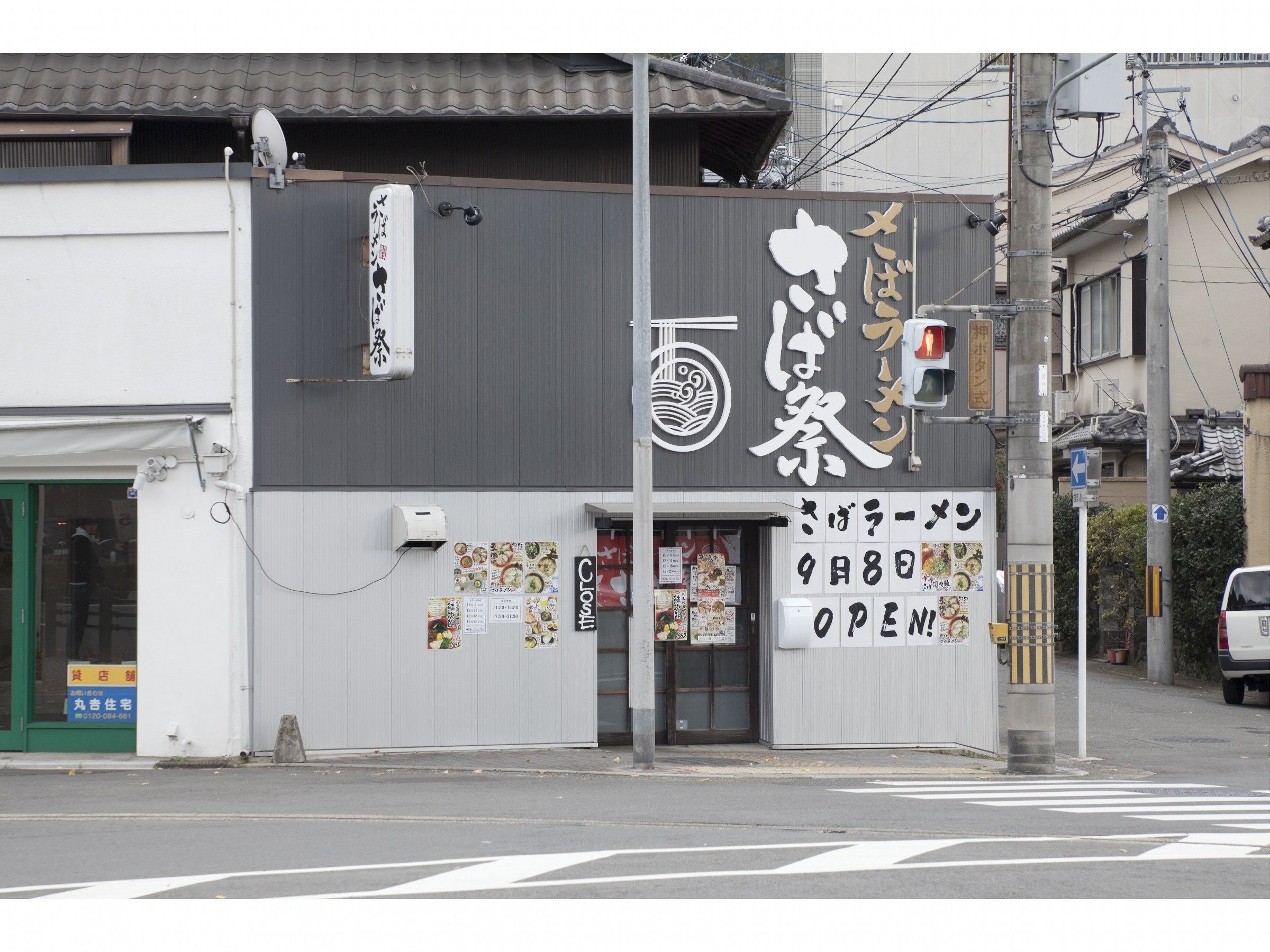A building with a large sign displaying Japanese characters and a smaller sign indicating the business is open.