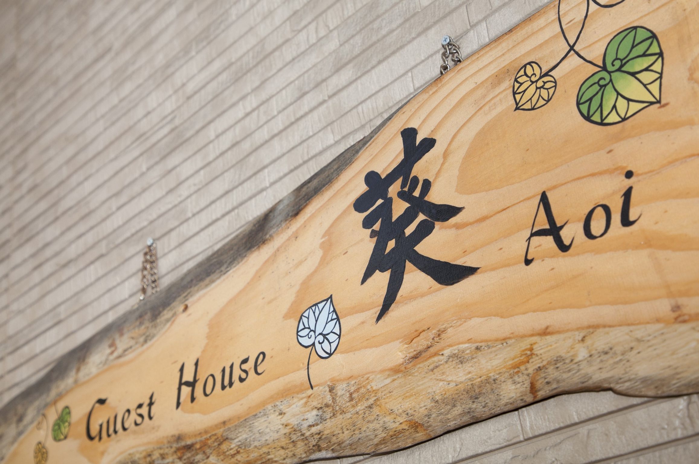 A wooden sign with Chinese characters and the words "Guest House" indicating a lodging facility.