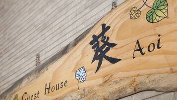 A wooden sign with Chinese characters and the words "Guest House" indicating a lodging facility.