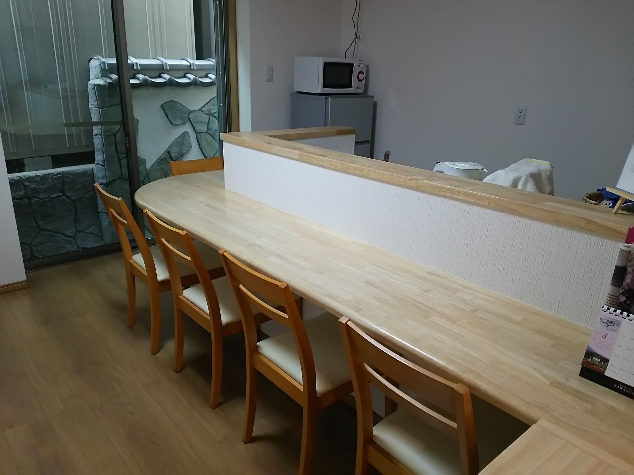 A compact kitchen with a microwave, a refrigerator, and a dining area with a wooden table and chairs.