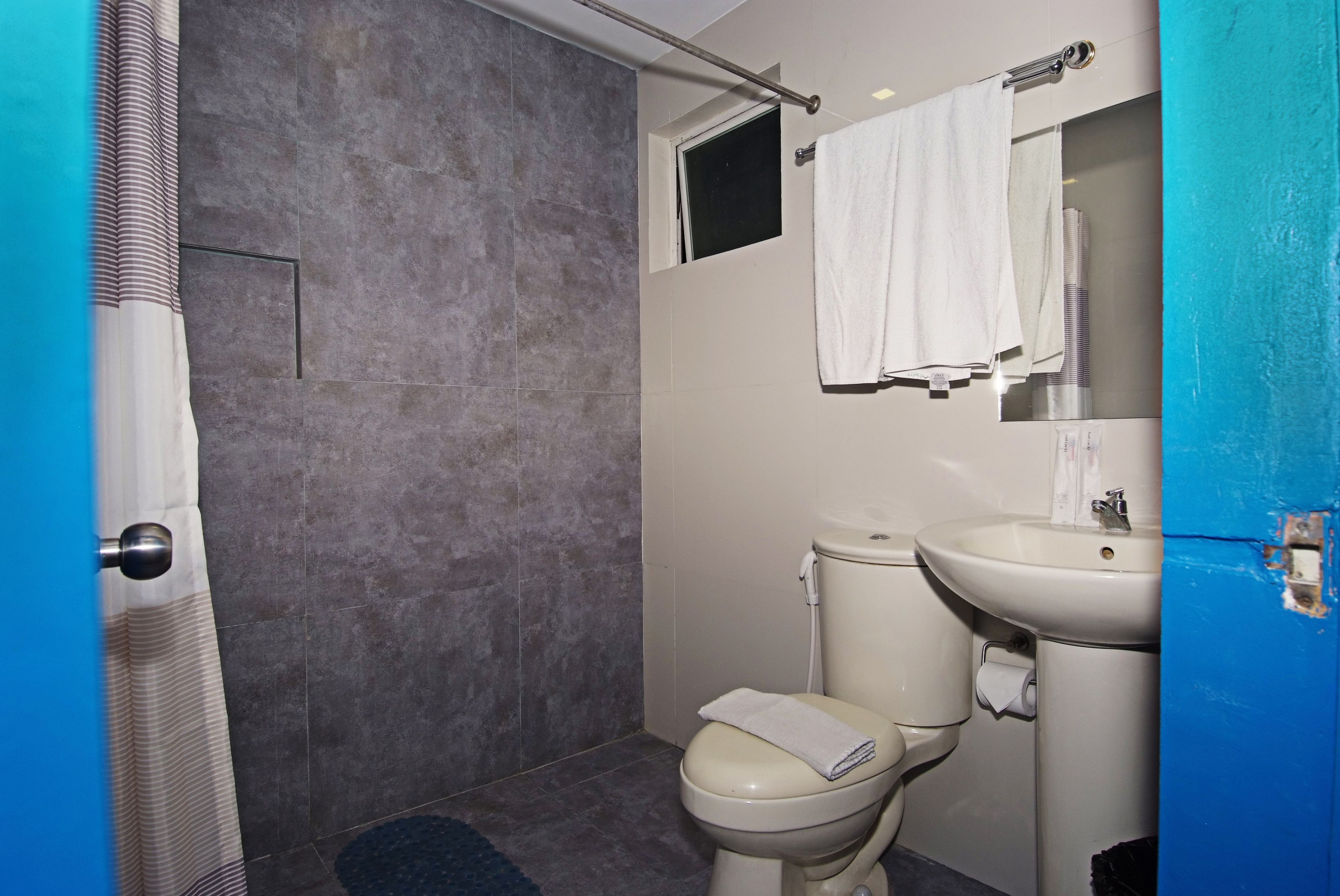 A bathroom with a shower, toilet, sink, and a towel rack.