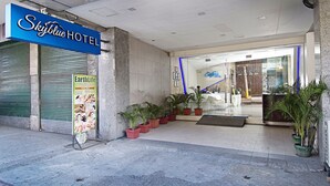 Ingången till Skyblue Hotel med en skylt, en annons för ett spa och krukväxter.