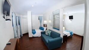 Ett hotellrum med en säng, en soffa, en tv och ett skrivbord.