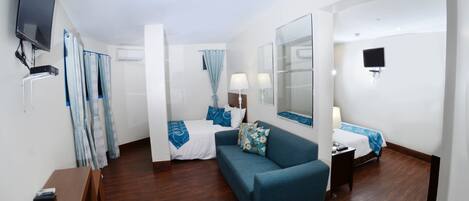 A hotel room with a bed, a sofa, a TV, and a desk.
