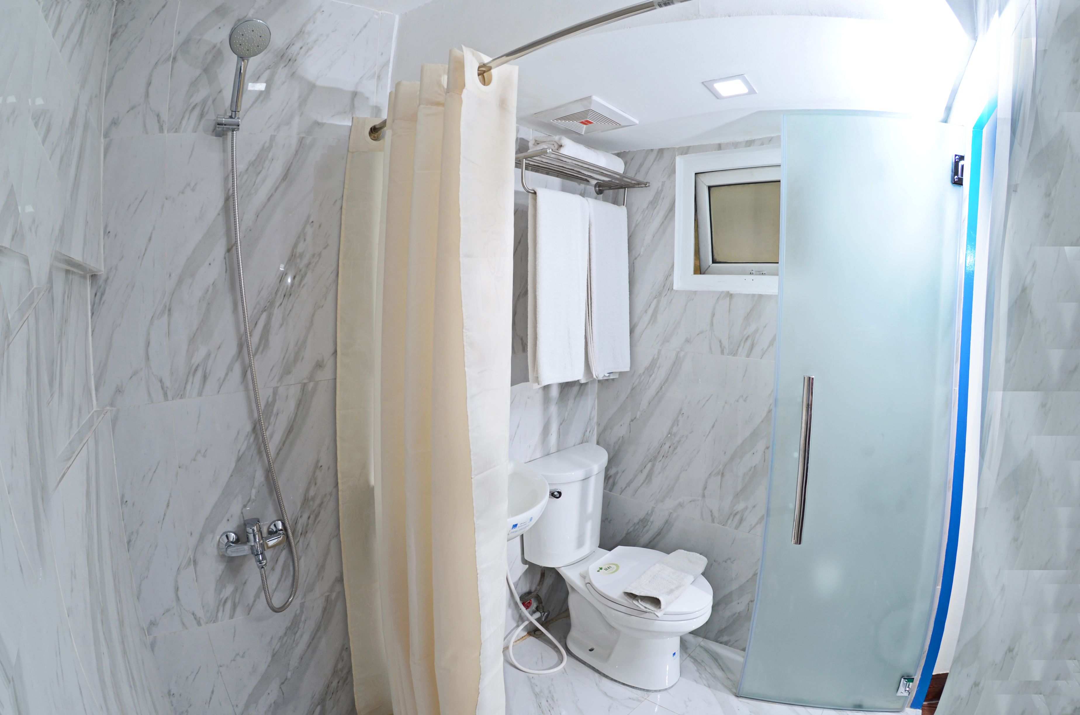 A bathroom with a shower, toilet, and a glass-enclosed shower stall.