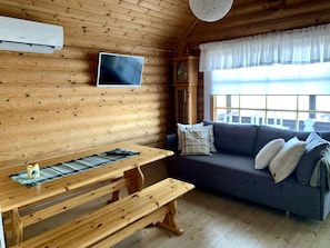 Relax in this cozy cabin-style room with a dining table, comfortable sofa, and mounted TV for entertainment.