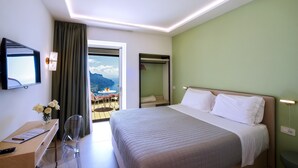 Una habitación de hotel con cama, escritorio, silla, televisor y vistas a las montañas.