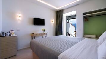 A modern hotel room with a large bed, a desk, a flat-screen TV, and a view of the outdoors.