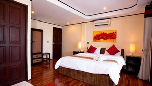 Ein Schlafzimmer mit einem großen Bett, zwei Nachttischen, einem roten Teppich und einer Wandklimaanlage.