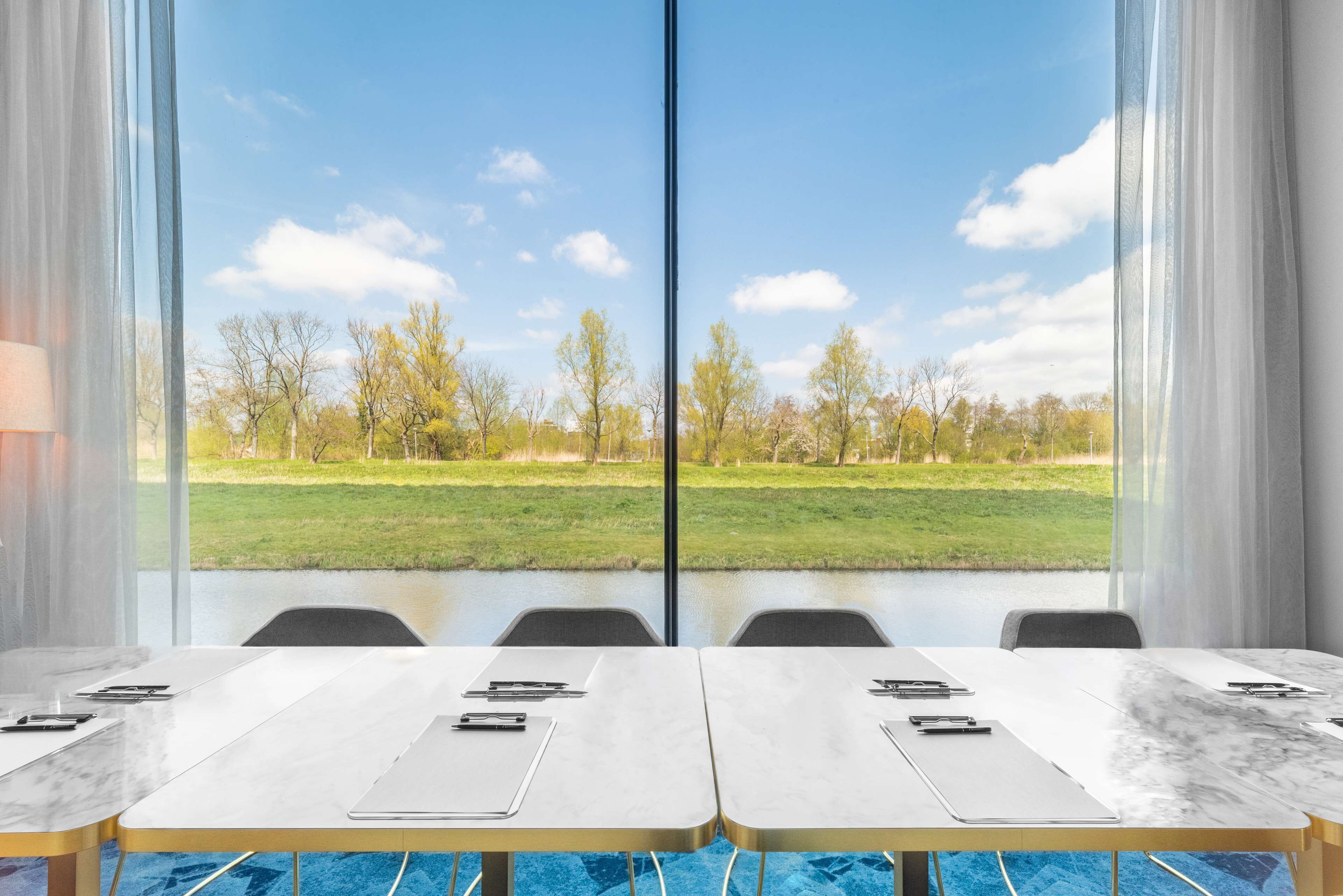 Una sala conferenze con un'ampia finestra che si affaccia su un prato e alberi.