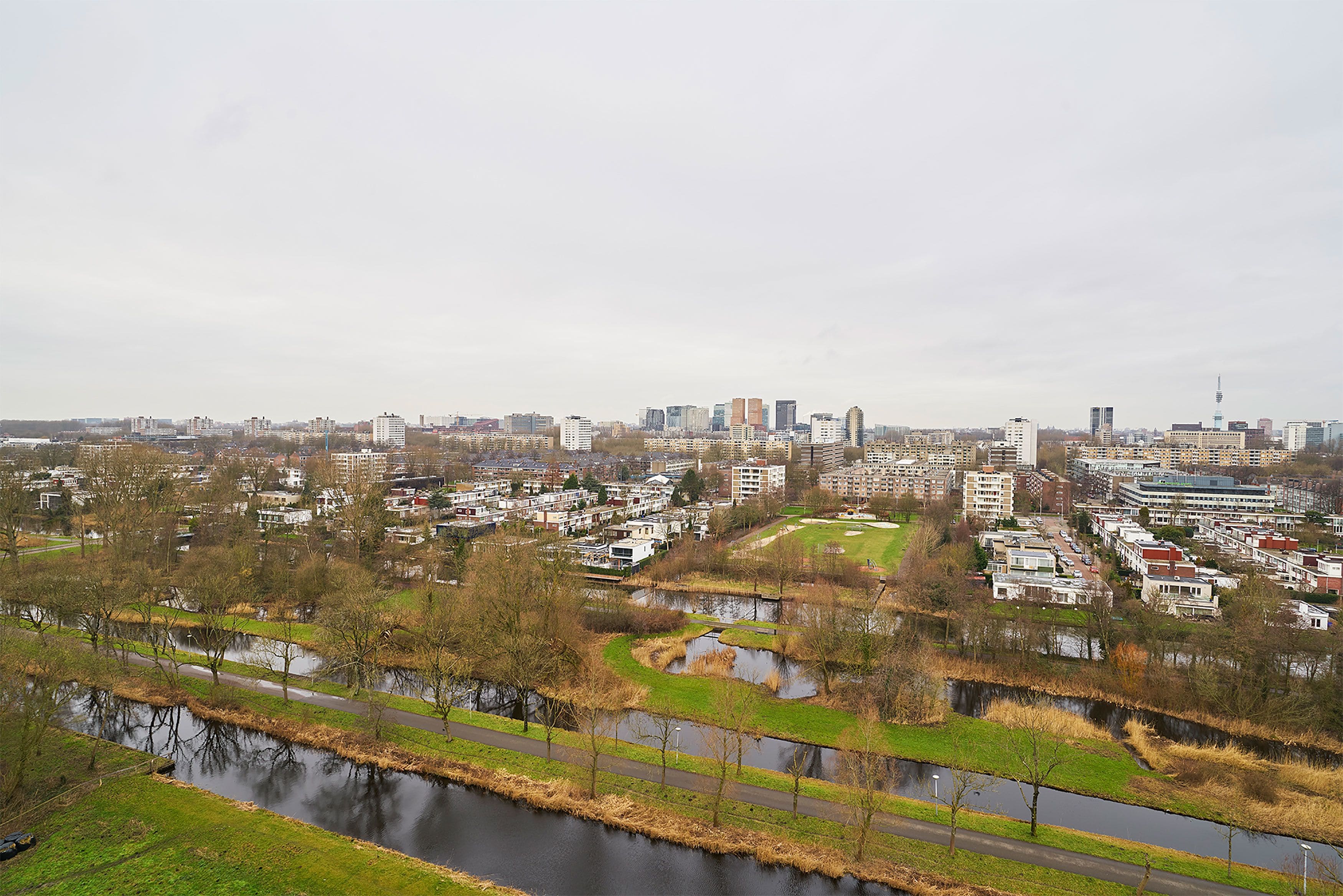 Eine Stadtansicht mit einem Fluss, Wohnhäusern und einem markanten Turm.