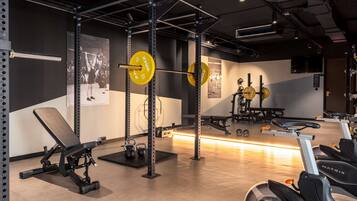Une salle de sport équipée de matériel de musculation, de tapis de course et d’un banc.