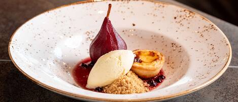 A dessert plate with a pear, ice cream, and a tart on a speckled ceramic plate.