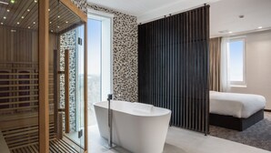 A modern bathroom with a freestanding bathtub, a glass shower enclosure, and a large window. - Radisson Hotel & Suites Amsterdam South (Amstelveen)