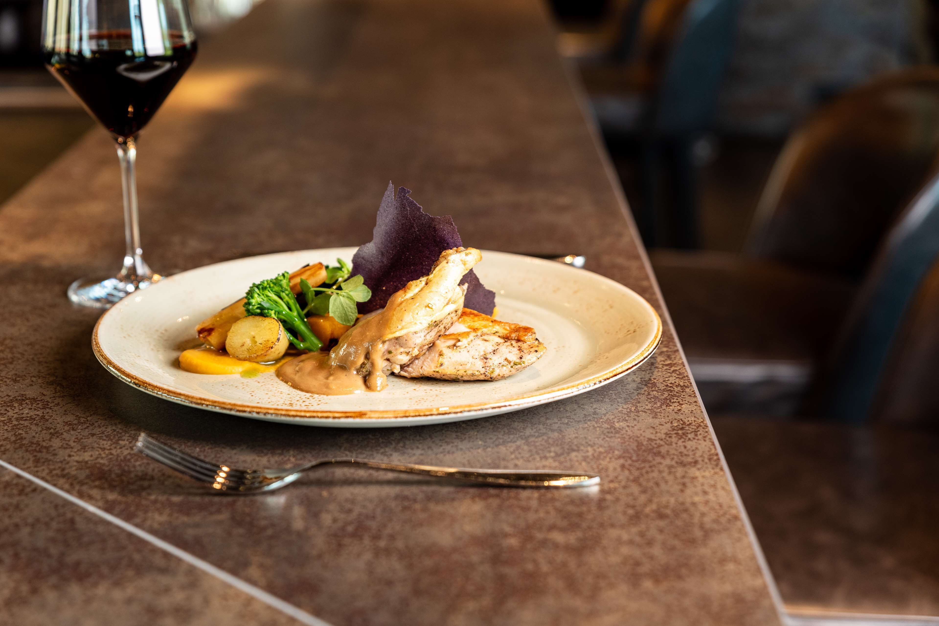 A plate of food with a glass of red wine on a table.