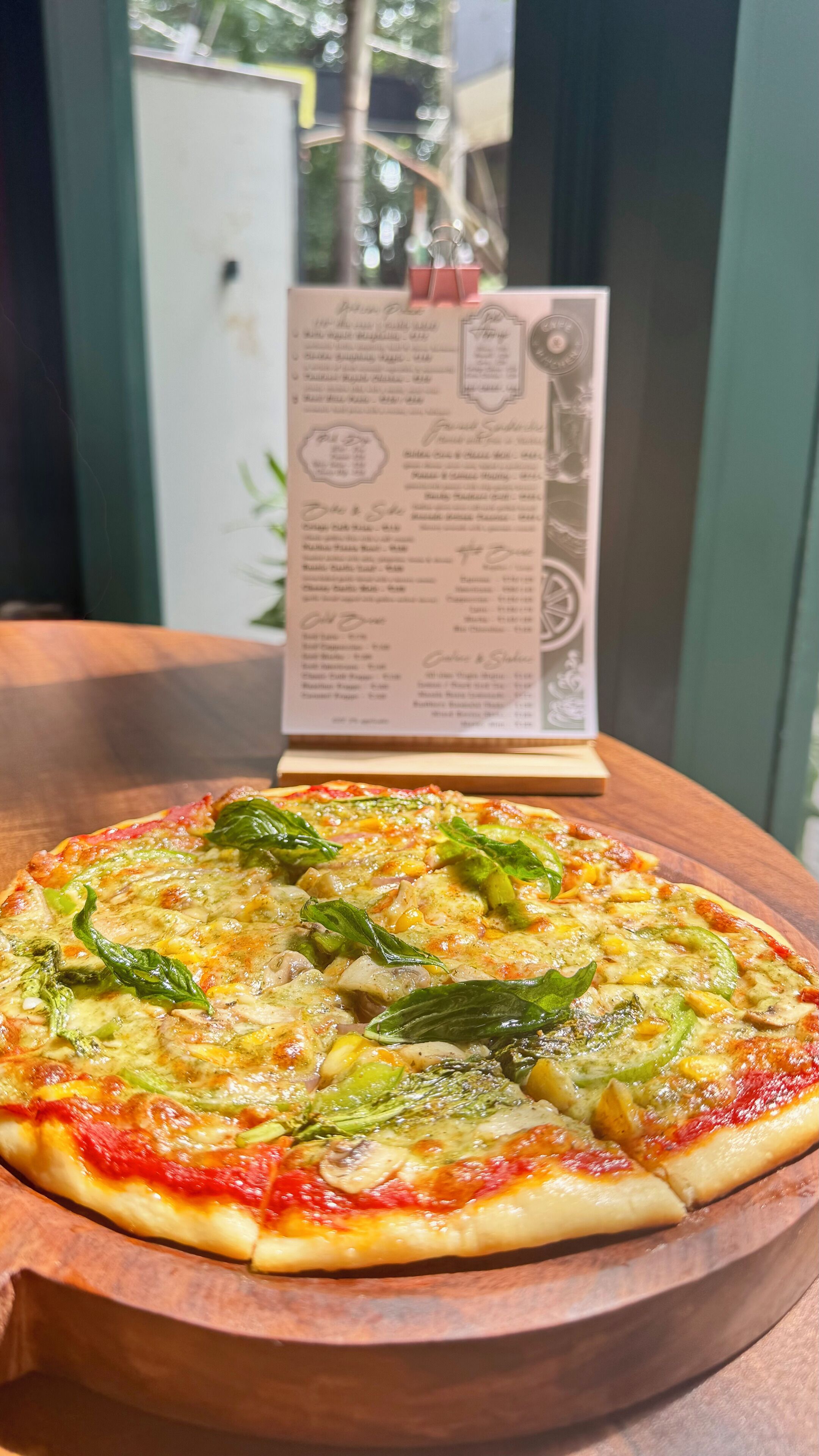 A pizza on a wooden board with a menu in the background.