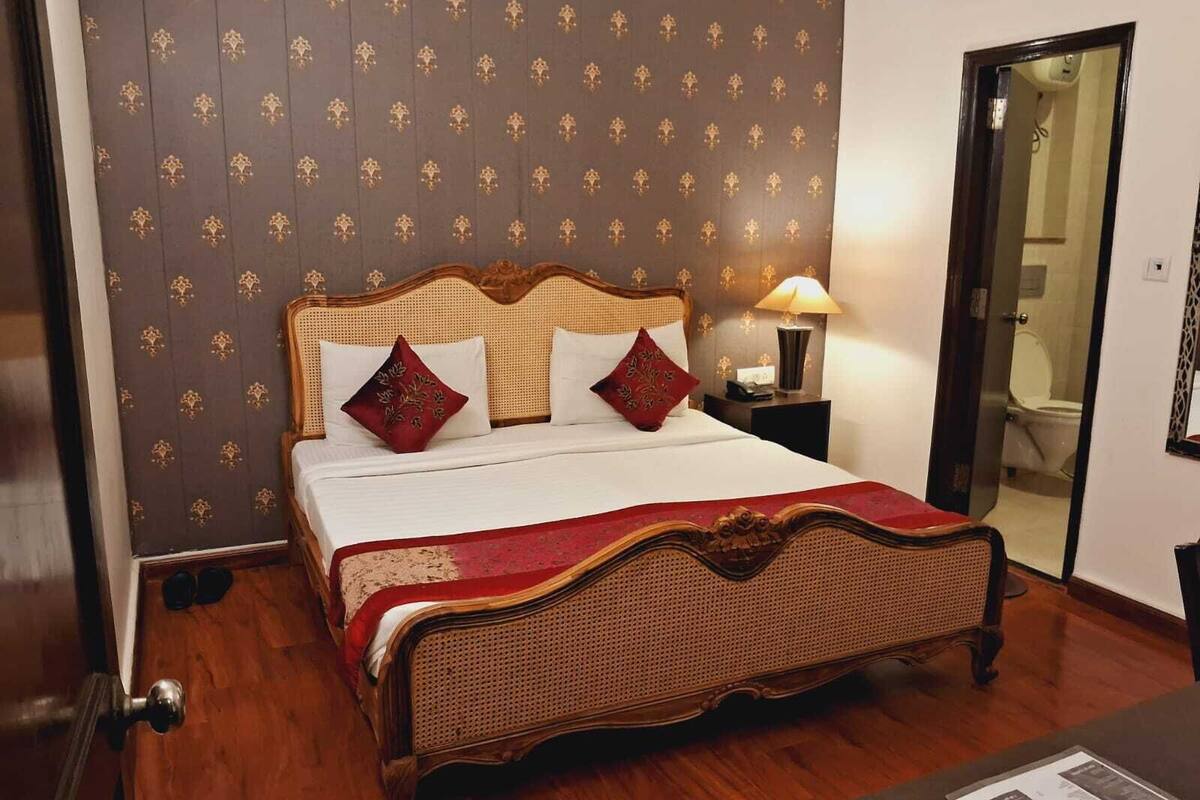 A bedroom with a wooden bed, a nightstand, a lamp, and a mirror.