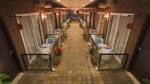 A hotel corridor with multiple rooms, each with a toilet, a bench, and potted plants. - Sinon Baga Retreat (Baga)