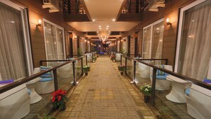 A corridor with a tiled floor, potted plants, and wicker furniture along the sides. - Sinon Baga Retreat (Baga)