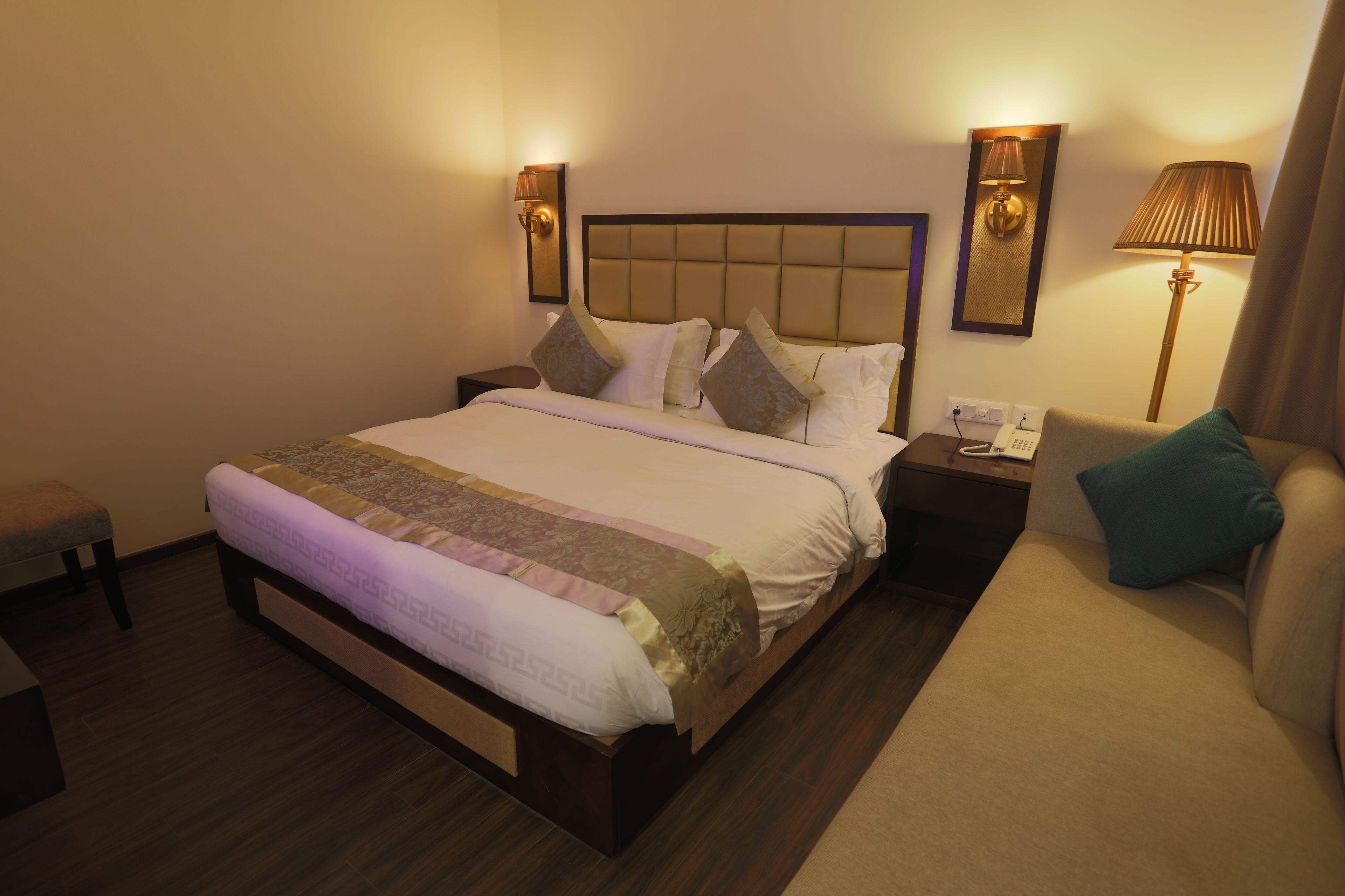 A hotel room with a large bed, two bedside tables, a nightstand, a chair, and a lamp.