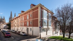 A red building with a large window and a blue handicap parking sign. - Apartamentos El Cid (Burgos)