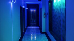 Un pasillo con iluminación azul, suelo de mármol y un diseño decorativo en la pared.