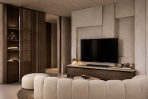 En moderne stue med et fladskærms-tv monteret på væggen, et træskab med en lampe og en beige sofa.