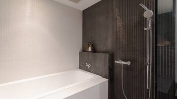 A modern bathroom with a white bathtub, a shower with a handheld showerhead, and a tiled wall.