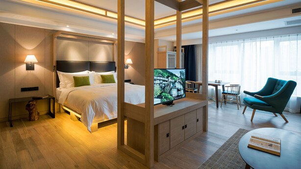 A modern hotel room with a large bed, a TV, a desk, a chair, and a window with curtains. - Harbin 22C Boutique Hotel (Harbin)