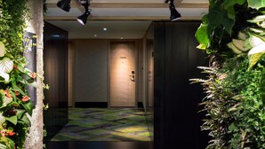 A hallway with a patterned carpet, a wooden door labeled "1920", and plants on either side. - Harbin 22C Boutique Hotel (Harbin)
