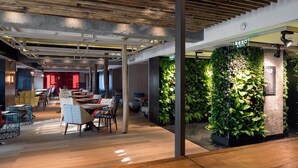 A modern interior with wooden ceiling beams, a green wall with plants, and a sign indicating an exit. - Harbin 22C Boutique Hotel (Harbin)