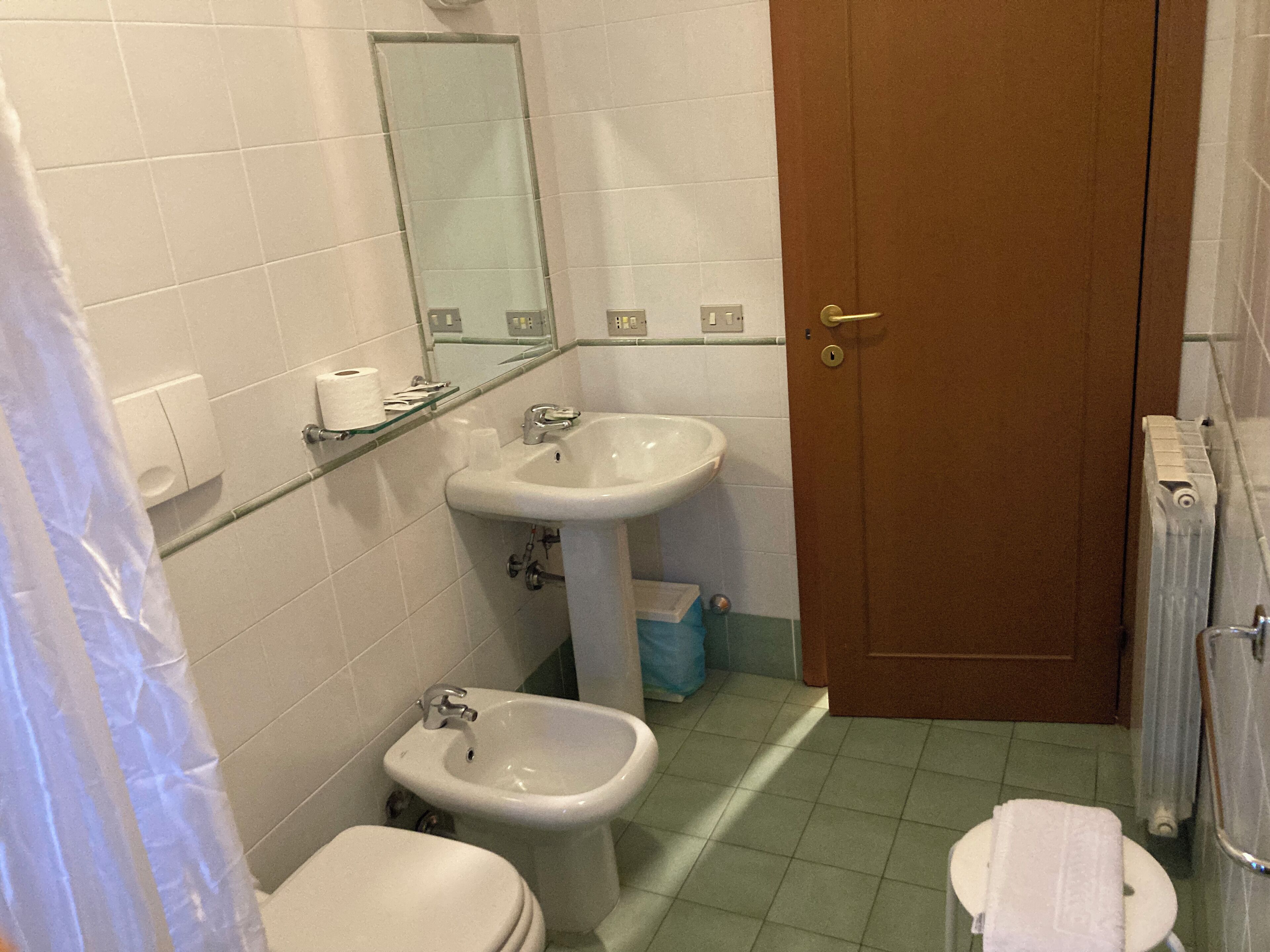 Une salle de bain équipée de toilettes, d’un bidet, d’un lavabo et d’un miroir.