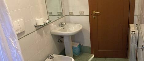 Une salle de bain équipée de toilettes, d’un bidet, d’un lavabo et d’un miroir.