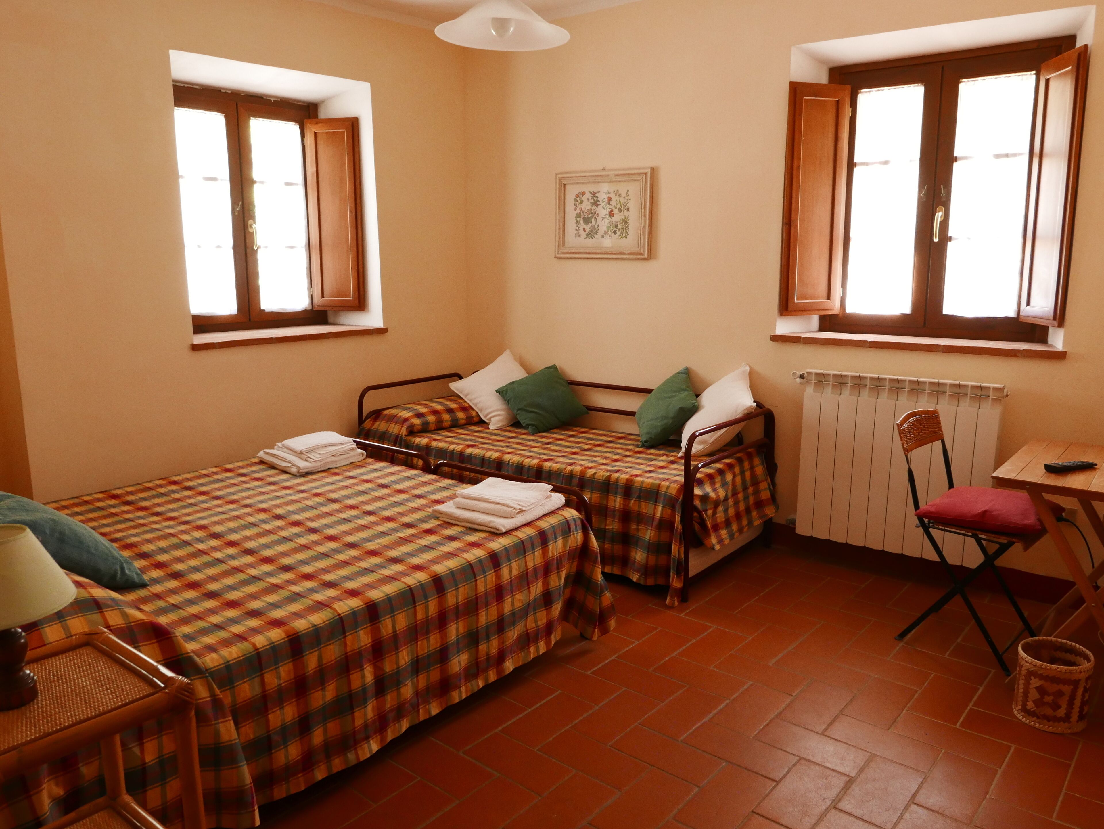 Une petite pièce avec deux lits, un radiateur, une chaise et une table.