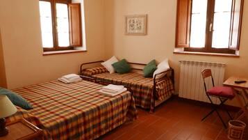 Une petite pièce avec deux lits, un radiateur, une chaise et une table.
